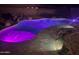 Inviting backyard pool with decorative rock waterfall feature and stone tile surround at 15019 W Banff Ln, Surprise, AZ 85379