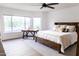 Bright main bedroom with a ceiling fan, light hardwood floors, a large bed, and a workstation near the large picture window at 19276 N 90Th Pl, Scottsdale, AZ 85255