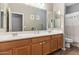 Bathroom featuring double sinks with wooden cabinetry, a large mirror, and tiled floor at 2237 S Jacana Ln, Gilbert, AZ 85295