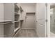 Spacious walk-in closet with built-in shelving and carpet, leading to tiled shower at 26753 W Zachary Dr, Buckeye, AZ 85396
