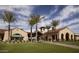 Inviting clubhouse exterior with lush landscaping, palm trees, and manicured lawn at 26753 W Zachary Dr, Buckeye, AZ 85396