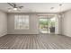 Bright living room featuring wood floors, shuttered windows, and sliding glass doors at 26753 W Zachary Dr, Buckeye, AZ 85396