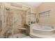 Bright bathroom featuring tile shower, soaking tub, and decorative glass block window at 3166 N 158Th Ave, Goodyear, AZ 85395