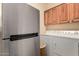 Bright laundry room with stainless steel fridge and white washer/dryer appliances with upper cabinets at 3166 N 158Th Ave, Goodyear, AZ 85395