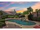 A stunning pool with a rock waterfall feature surrounded by lush landscaping and a captivating sunset sky at 4428 E Yawepe St, Phoenix, AZ 85044