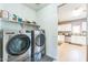 Laundry room with stainless steel washer and dryer, shelf storage, and access to kitchen at 45173 W Sandhill Rd, Maricopa, AZ 85139