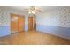 Bedroom with floral wallpaper, wood-look floors, ceiling fan and closet at 5228 E Des Moines St, Mesa, AZ 85205