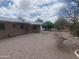 Backyard featuring desert landscaping, a covered patio, and partial views of mature trees in the distance at 5702 E Casper Rd, Mesa, AZ 85205