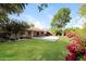 Beautiful backyard with lush green grass, mature trees, colorful flowers, and covered patio at 6126 W Paradise Ln, Glendale, AZ 85306