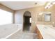 Well-lit bathroom with double vanity, separate tub, and shower, with tile flooring and arched doorway at 6126 W Paradise Ln, Glendale, AZ 85306