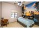 This bedroom is complete with unique ceiling fan, window and a wall displaying a custom wall-sized tropical mural at 6334 E Albany St, Mesa, AZ 85205