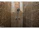 Close up of a tiled shower with adjustable shower head and neutral stone accents at 6334 E Albany St, Mesa, AZ 85205