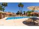 Community pool with lounge chairs, tables and chairs, surrounded by palm trees at 7040 W Olive Ave # 94, Peoria, AZ 85345