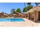 Community pool surrounded by lush greenery with lounge chairs, tables and umbrellas for shade at 7040 W Olive Ave # 94, Peoria, AZ 85345