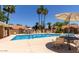 Community pool with lounge chairs, tables and chairs, surrounded by palm trees at 7040 W Olive Ave # 94, Peoria, AZ 85345