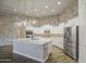 Modern kitchen with white cabinets, stainless steel appliances, large island, and decorative pendant lighting at 710 W Ardmore Rd, Phoenix, AZ 85041