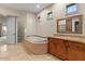 Elegant bathroom featuring a soaking tub, wood cabinetry, granite countertops and multiple windows at 8540 E Mcdowell Rd # 119, Mesa, AZ 85207