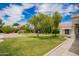 Lush backyard with a vibrant green lawn, mature trees, and a peaceful patio area at 10130 E San Salvador Dr, Scottsdale, AZ 85258