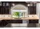 Elegant kitchen with dark wood cabinets, granite countertops, and a stainless steel dishwasher at 10130 E San Salvador Dr, Scottsdale, AZ 85258