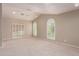 Bright living room with neutral carpet, two arched windows, and sliding door to the patio at 10130 E San Salvador Dr, Scottsdale, AZ 85258