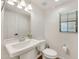 Powder room featuring a pedestal sink, decorative mirror, and natural light at 10428 E Nopal Ave, Mesa, AZ 85209