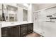 Bathroom featuring double sinks with dark wood cabinets and a glass-enclosed shower at 10428 E Nopal Ave, Mesa, AZ 85209
