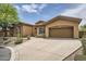 Side view of a tan single-story home with a two-car garage and desert landscaping at 12448 N 129Th Pl, Scottsdale, AZ 85259