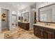 Bathroom with dual sinks, stone floors, wooden cabinets, and a view into a bedroom at 1409 E Dove Pl, Casa Grande, AZ 85122