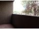 The covered patio has a textured wall and a view of foliage, vehicles, and nearby buildings at 151 E Broadway Rd # 210, Tempe, AZ 85282
