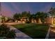 Enjoy this backyard featuring lush green grass, mature trees, ambient lighting, and a brick paver patio at 1725 E Everglade Ln, Gilbert, AZ 85298
