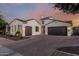 Stunning single-story home featuring a paver driveway and a three-car garage, set against a vibrant sunset sky at 1725 E Everglade Ln, Gilbert, AZ 85298