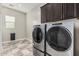 The laundry room features modern tile flooring, upper cabinets, and a modern washer and dryer at 1725 E Everglade Ln, Gilbert, AZ 85298