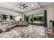 Open-concept living room with tile floors, a large leather couch, a ceiling fan, and a sliding glass door at 1725 E Everglade Ln, Gilbert, AZ 85298