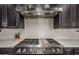 Stainless steel range with white backsplash, overhead vent, and black cabinets at 1725 E Everglade Ln, Gilbert, AZ 85298