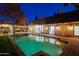 Relaxing backyard pool featuring a dining area and sun loungers, beautifully illuminated at night at 18 W Kaler Dr, Phoenix, AZ 85021