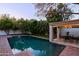 Backyard featuring a sparkling pool, outdoor dining area, and lush landscaping for ultimate relaxation and entertainment at 18 W Kaler Dr, Phoenix, AZ 85021