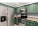 Well lit kitchen with stainless steel appliances and green cabinets, creating a refreshing cooking space at 2121 W Union Hills Dr # 113, Phoenix, AZ 85027