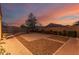 Large backyard showcasing a brick patio, gravel accents, and a basketball hoop at dusk at 2324 W Melody Dr, Phoenix, AZ 85041