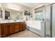 Well-lit bathroom boasts a double vanity, a separate tub, a tiled floor, and natural light at 2324 W Melody Dr, Phoenix, AZ 85041