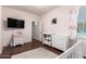 Bedroom with hardwood floors features changing table, white dresser, and small television set at 2324 W Melody Dr, Phoenix, AZ 85041