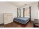 Well-lit bedroom boasts hardwood floors, a large window, and white dresser with soft, natural light at 2324 W Melody Dr, Phoenix, AZ 85041
