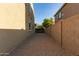 View of the gravel-covered side yard between houses, enclosed by a tall block wall with a wooden gate at 2324 W Melody Dr, Phoenix, AZ 85041