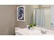 Well-lit bathroom with a white vanity, framed artwork, and a shower with a patterned curtain at 23362 W Atlanta Ave, Buckeye, AZ 85326