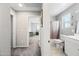 Hallway view into a bathroom with shower-tub combo and large vanity; bedroom shown in background at 2387 E Runaway Bay Pl, Gilbert, AZ 85298