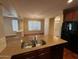 Kitchen island with double sink and granite countertops, with view of living room and windows at 26449 N 84Th Dr, Peoria, AZ 85383