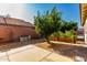 Well-kept backyard garden with retaining wall, lush tree and partial patio at 4214 W Marco Polo Rd, Glendale, AZ 85308