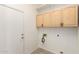 Bright laundry room features wooden cabinets, white walls, gray tile flooring, and a utility sink hookup at 4214 W Marco Polo Rd, Glendale, AZ 85308