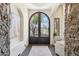A luxurious foyer with ornate iron double doors, stone accent wall, and elegant lighting create a grand entrance at 5402 E Cortez Dr, Scottsdale, AZ 85254