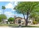Elegant home with a well-manicured lawn, mature trees, and a grand entrance with arched doorway and a stone accent chimney at 5402 E Cortez Dr, Scottsdale, AZ 85254