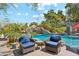 Tranquil poolside patio featuring comfortable chairs, a small table, and views of the lush waterfall pool area at 5402 E Cortez Dr, Scottsdale, AZ 85254